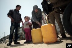 FILE - A Palestinian family fill plastic gallons with drinking water they bought from a vendor in Khan Younis refugee camp, southern Gaza Strip.