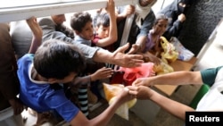 People crowd to get food rations from a charity kitchen in Sana'a, Yemen, July 20, 2020.