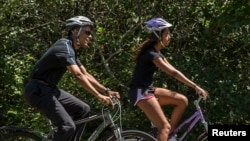 Presiden AS Barack Obama bersepeda besama anaknya Malia ketika berlibur di kebun anggur Martha di Massachusetts, 15 Agustus 2014. 