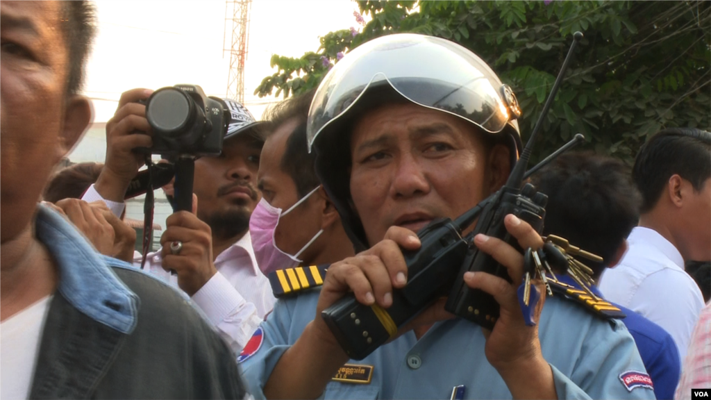 A traffic police officer talks on his walkie-talkie to facilitate the traffic for the demonstrators during the protest against CNRP&#39;s acting president, Kem Sokha. (Pin Sisovann/VOA Khmer)