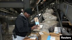 FILE - United Parcel Service employee Xolilel Moyo works to load packages at the UPS Worldport All Points International Hub during the peak delivery season in Louisville, Kentucky, Dec. 9, 2016. 