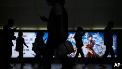 Commuters walk by a computer and mobile phone's RPG games advertisement at a subway station in Beijing Tuesday, Sept. 14, 2021. (AP Photo/Andy Wong) 