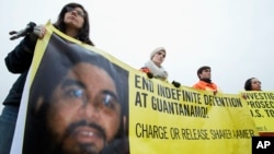 FILE - Human rights activists hold a banner with a picture of Shaker Aamer during a rally near the White House in Washington, Jan. 11, 2013. Aamer was freed last October.