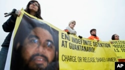 Para aktivis HAM membawa spanduk bergambar Shaker Aamer saat berunjuk rasa di Washington, 11 Januari 2013 (Foto: dok). Warga Inggris terakhir yang telah mendekam sejak 2002 di penjara AS di Teluk Guantanamo, Kuba, tersebut telah dibebaskan, Jumat (30/10).