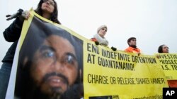 FILE - Human rights activists hold a banner with a picture of Shaker Aamer. The last British resident of the U.S. prison in Guantanamo Bay in Cuba has been released.