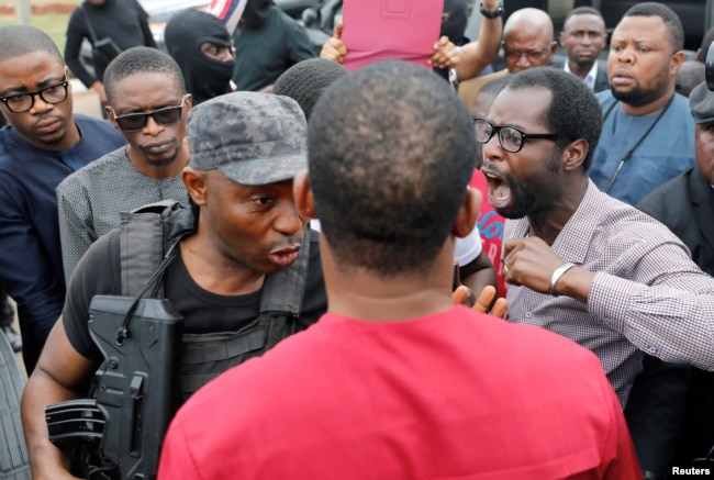 A man reacts next to a member of security forces at the entrance of the National Assembly in Abuja, Nigeria, Aug. 7, 2018.
