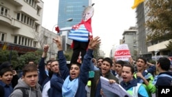FILE - Iranian schoolboys chant slogans while holding an effigy of U.S. President Donald Trump in an annual gathering in front of the former U.S. Embassy marking the anniversary of its 1979 takeover, in Tehran, Iran, Nov. 4, 2017.