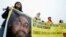 FILE - Human rights activists hold a banner with a picture of Shaker Aamer.