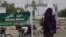 FILE- In this April 15, 2011, file photo, a Muslim woman walks past an Arabic sign on a street which reads 'God is great' in Katsina, Nigeria.
