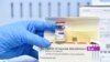  Seorang petugas layanan kesehatan menunjukkan botol dan sekotak vaksin AstraZeneca, 19 Maret 2021. (Foto: REUTERS/Massimo Pinca)