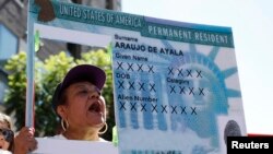A woman holds a replica green card sign during a protest march to demand immigration reform in Hollywood, Los Angeles, California, October 5, 2013. 