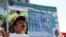 A woman holds a replica green card sign during a protest march to demand immigration reform in Hollywood, Los Angeles, California, October 5, 2013. 