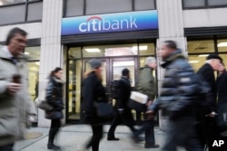 FILE - People walk past a branch office of Citibank in New York, Jan. 15, 2015.