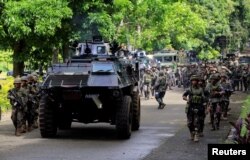 FILE - An armored personnel carrier and government troops march to begin their assault with insurgents from the so-called Maute group, who have taken over large parts of Marawi City, southern Philippines, May 25, 2017.