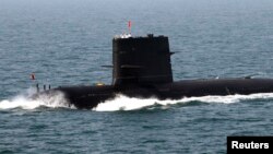 FILE - Chinese sailors salute on top of a submarine during the fleet's review of the China-Russia joint naval exercise in the Yellow Sea.