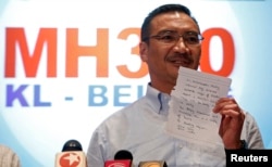 Malaysia's acting Transport Minister Hishammuddin Hussein holds up a note that he has just received on a new lead in the search for the missing Malaysia Airlines Flight MH370, during a news conference at Kuala Lumpur International Airport, Mar. 22, 2014.