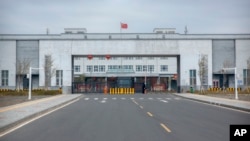 FILE - Police officers stand at the entrance of the Urumqi No. 3 Detention Center in Dabancheng in China's Xinjiang Uyghur Autonomous Region on April 23, 2021. Urumqi No. 3, is China's largest detention center has room for at least 10,000 inmates.