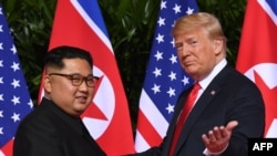 US President Donald Trump (R) gestures as he meets with North Korea's leader Kim Jong Un (L) at the start of their historic US-North Korea summit, at the Capella Hotel on Sentosa island in Singapore