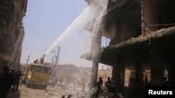 Civil defence members try to put out a fire after what activists claim was a car explosion in a market in central Douma in the eastern al-Ghouta, near Damascus June 28, 2014