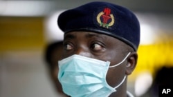 FILE - A Nigerian health official wearing a protective mask waits to screen passengers at the arrivals hall of Murtala Muhammed International Airport in Lagos, Nigeria.
