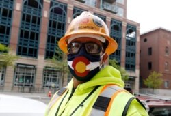 Construction worker Jesus Bejarano wears a face mask bearing the design of the flag of Colorado as he heads back to work May 9, 2020, in Denver, Colo.