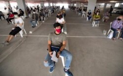 Tourists practice social distancing as they wait to extend their visa at Immigration Bureau in Bangkok, Thailand, March 27, 2020.