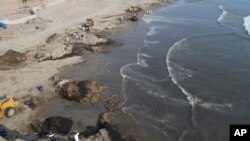 Trabajadores limpian un derrame de petróleo en la playa Cavero en Ventanilla, Callao, Perú, el lunes 17 de enero de 2022. 