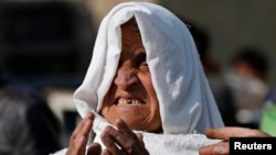 FILE - A woman mourns as she looks for her relatives at the site of a suicide attack in Kabul, Afghanistan, Nov. 27, 2014. 