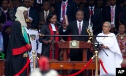 FILE - Kenyan President Uhuru Kenyatta, center, is sworn-in, accompanied by his wife Margaret, right, during his inauguration ceremony at Kasarani stadium in Nairobi, Kenya, Nov. 28, 2017.