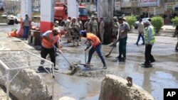 Para pekerja membersihkan puing-puing pasca serangan bom di distrik Shaab, di Baghdad, Irak akhir bulan lalu (30/5).