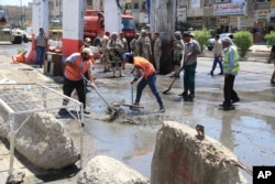 Municipality workers clean up debris in the aftermath of a bomb attack in Baghdad northern Shaab district, Iraq, May 30, 2016.