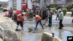 Para petugas membersihkan serpihan pasca serangan bom di distrik Shaab, Baghdad, Irak hari Senin (30/5). 
