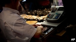 FILE - A man uses a cash register at a market in Madrid, Spain. 