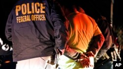 FILE - In this Oct. 22, 2018, photo U.S. Immigration and Customs Enforcement agents surround and detain a person during a raid in Richmond, Va. 