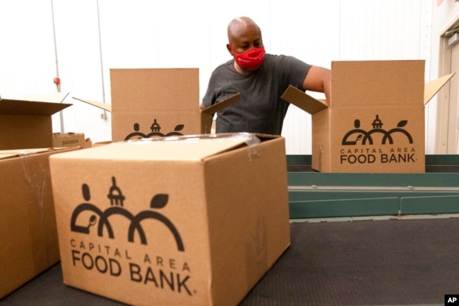 A volunteer pack boxes of food for distribution, at The Capital Area Food Bank, in Washington, Oct. 5, 2021.
