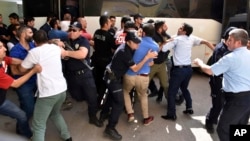 FILE - Police officers try to stop people attacking a judge believed to be member of a coup plotter group in Erzurum, Turkey, July 19, 2016. 