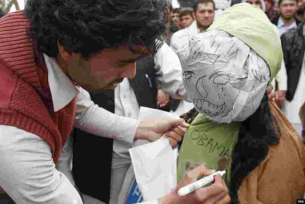 A demonstrator writes on an effigy depicting U.S. President Barack Obama before setting it on fire during a protest in Jalalabad. (AP)