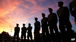 FILE: Indonesian police stand guard as activists stage a demonstration to demand the government to stop the execution of nine inmates, all convicted on drug charges, in Jakarta, Indonesia, Tuesday, April 28, 2015.