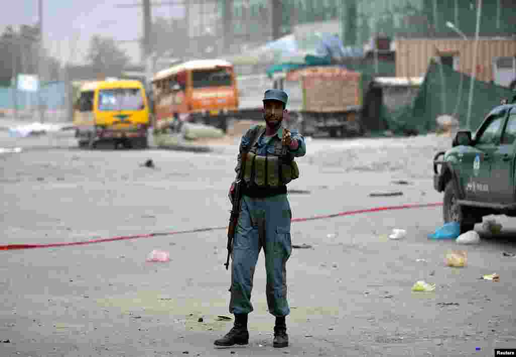 An Afghan police officer keeps watch at the site of bomb blasts in Kabul, June 6, 2014. 
