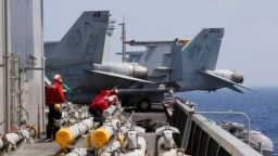2017年3月3日在南中国海例行巡航前，美国航母卡尔·文森号上的海军人员准备为F-18战斗机加装导弹。