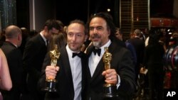 Emmanuel Lubezki, ganador del premio a la mejor fotografía por "The Revenant", a la izquierda, y Alejandro G. Inarritu, ganador del premio al mejor director de "The Revenant", aparecen detrás del escenario en los Oscar el domingo, 28 de febrero de 2016.