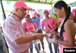 Soledad's Mayor Joao Herrera (L) gives a woman, condoms and kits with insect repellent during a campaign to fight the spread of Zika virus in Soledad municipality near Barranquilla, Colombia, in this Feb. 1, 2016 handout photo supplied by the Soledad Municipality.