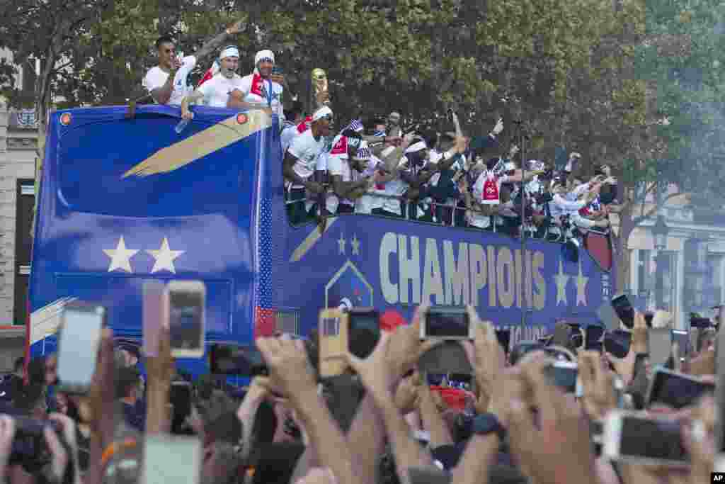Well-wishers cheer the victorious French team parading aboard a bus on the famed Champs Elysees avenue in Paris, France, after their 4-2 victory Sunday over Croatia to capture the trophy in the final of the FIFA World Cup, Monday, July 16, 2018. (AP Photo