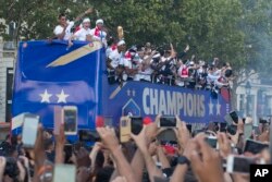 Para penggemar sepak bola menyambut timnas Perancis yang berparade menggunakan bus terbuka di sepanjang Champs-Elysees di Paris, Perancis, setelah menang atas Kroasia pada laga final Piala Dunia 2018, 16 Juli 2018.