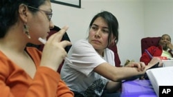 Theresa Rendon (C), originally from Mexico, now living in Queens borough of New York City and working as a housekeeper in New York, listens as Priscilla Gonzalez (L), a Domestic Workers United organizer, translates information from English to Spanish duri