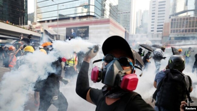 一名香港抗议者星期天（9-15-2019）向警方仍回一枚催泪弹。路透社