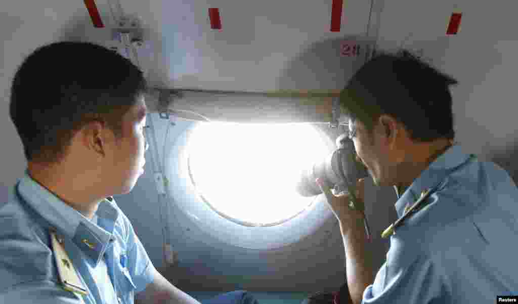 Uma equipa militar fotografa a partir de uma janela de um avião que pertence à Força Aérea Vietnamita durante a missão de busca e salvamento sobre a ilha do Tho Chu, do Vietname, Março 10, 2014. 