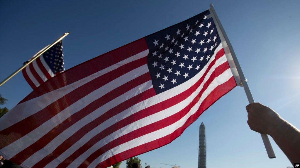 资料照：一人在华盛顿纪念碑附近挥舞美国国旗(photo:VOA)