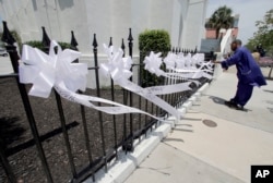 FILE - A man takes video of nine ribbons placed in front of the Mother Emanuel AME Church in Charleston, S.C., June 17, 2016, on the anniversary of the shooting deaths of nine black parishioners during a Bible study at the church.