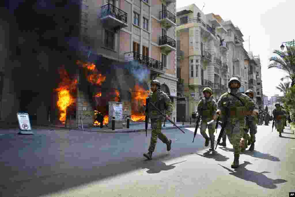 Lebanese army soldiers run in front of a Credit Libanais Bank that was set on fire by anti-government protesters, in the northern city of Tripoli.